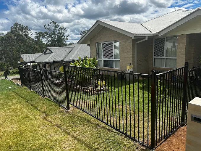 Finished black metal fencing around a landscaped home